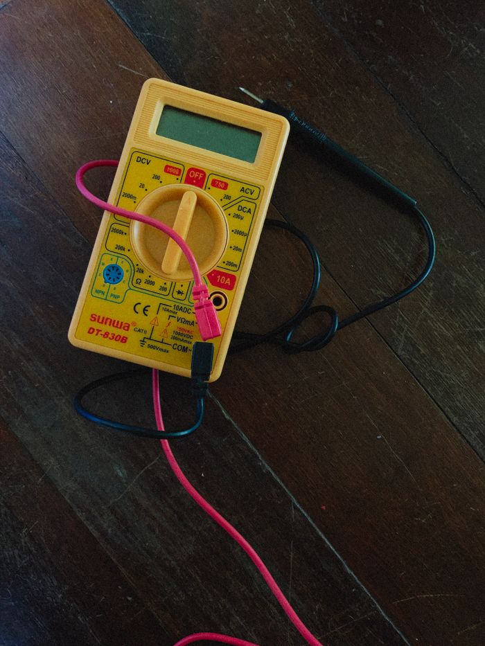 Mastering the First Impression: Your intriguing post title goes here A digital multimeter with wires on a wooden surface, focused view.