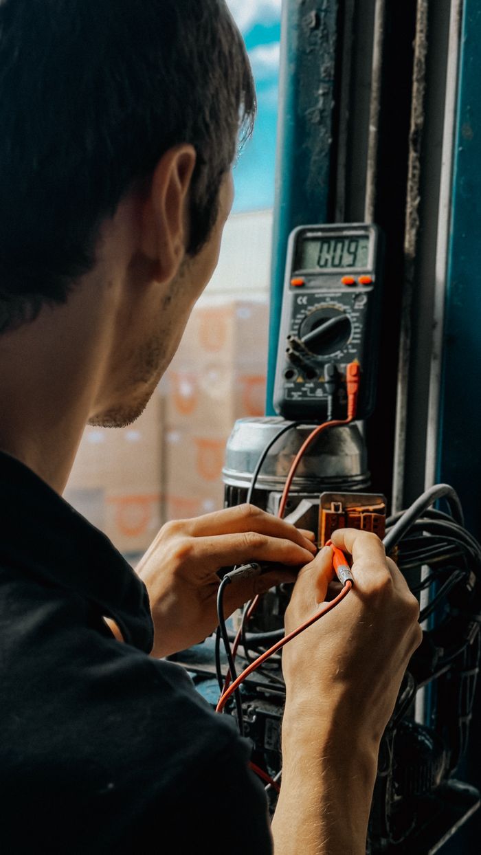 service-04 Electrician using a multimeter to check voltages in an industrial setting.