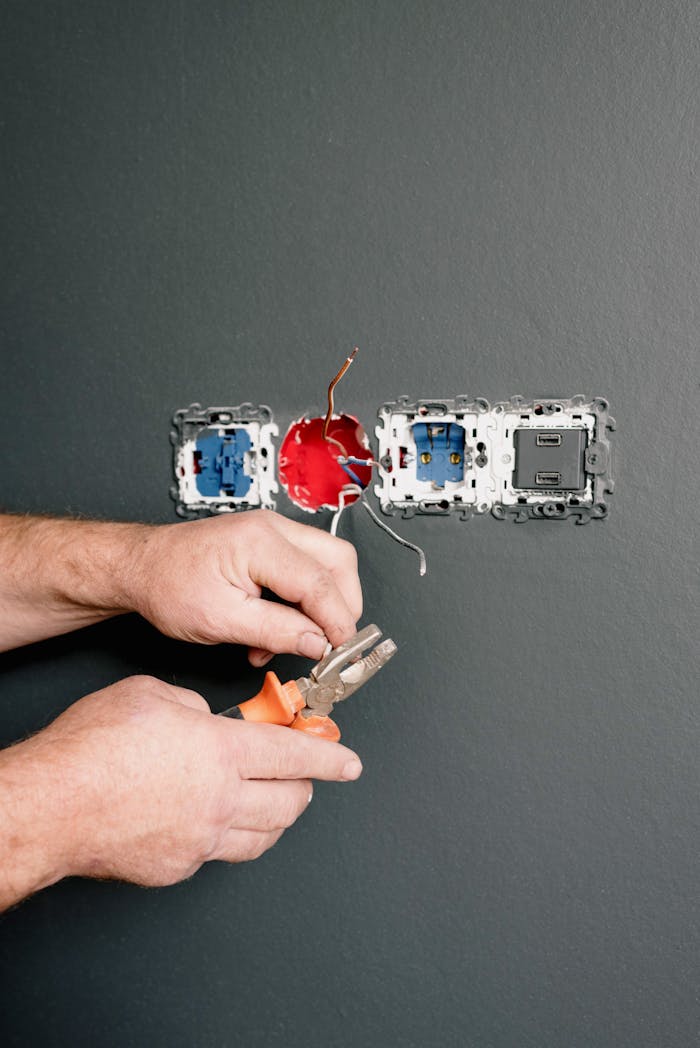service-02 Crop faceless electrician using pliers for installation sockets and switches in new apartment